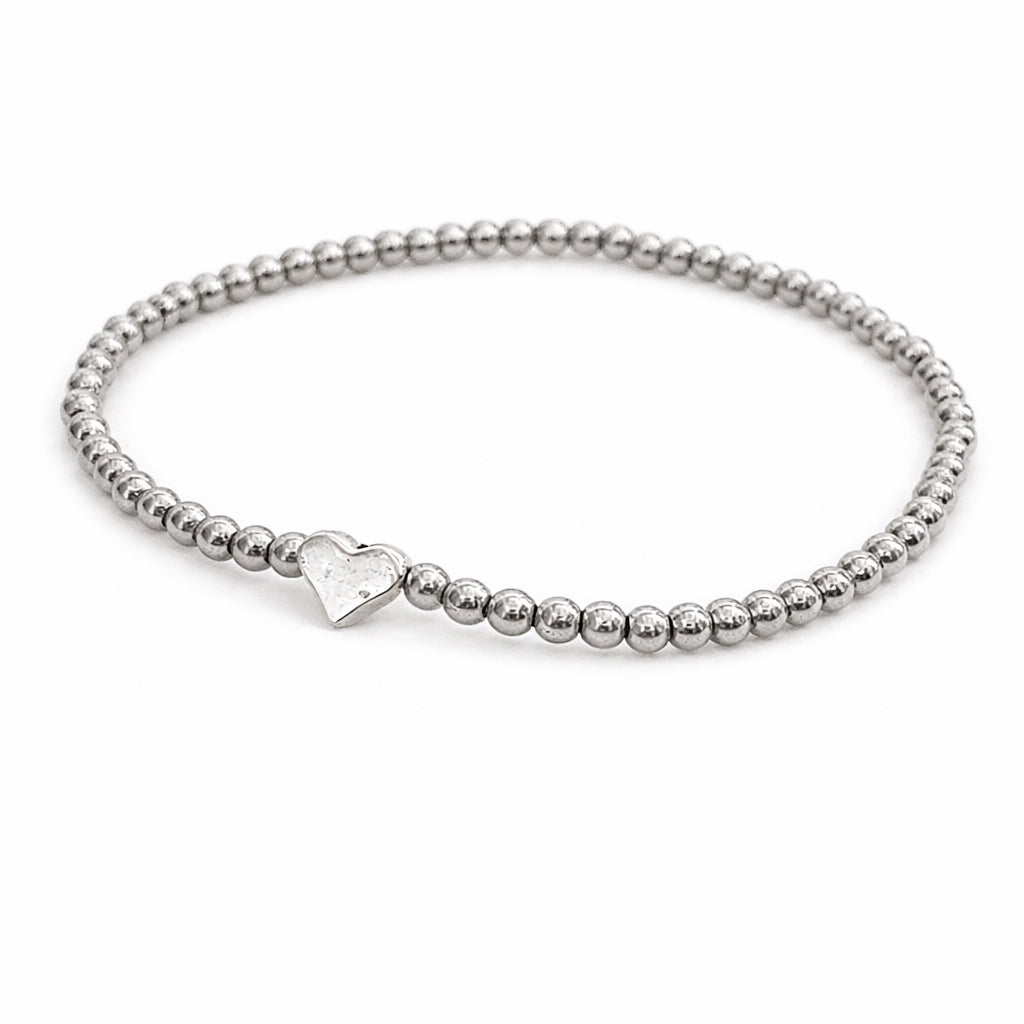 A silver-colored beaded bracelet with a heart-shaped charm attached.