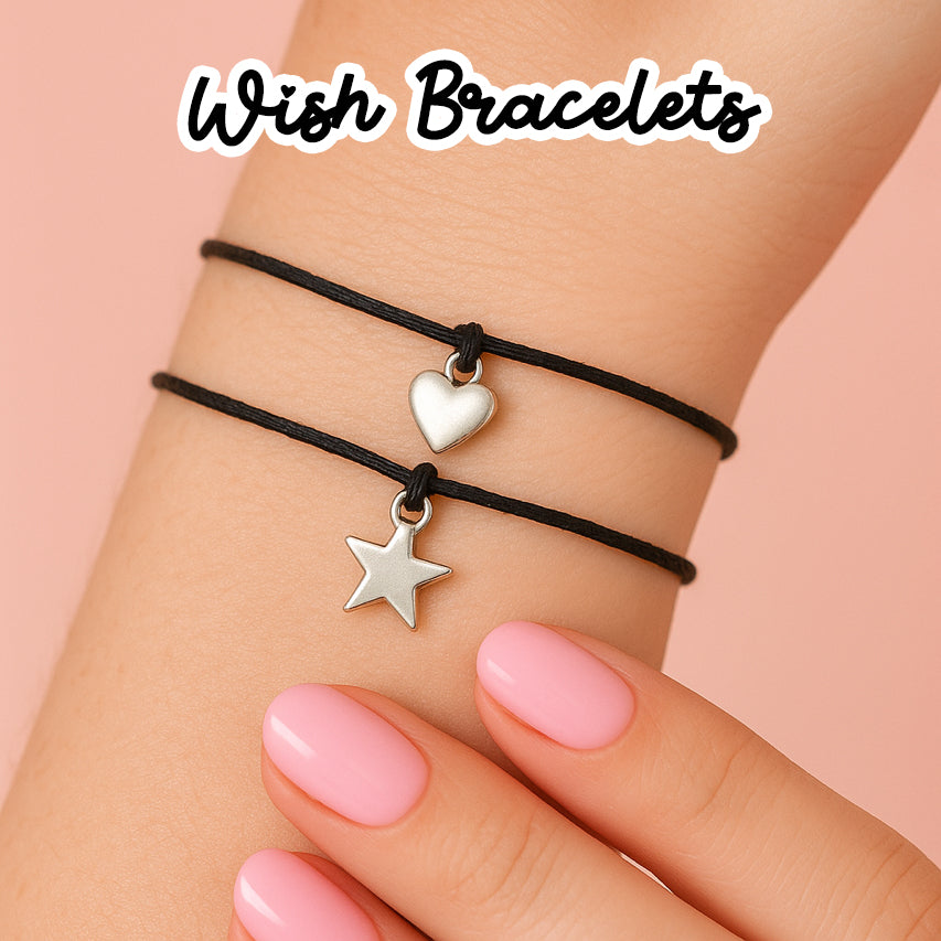 A close-up of a person's wrist wearing a black bracelet with a silver heart charm and a silver star charm.