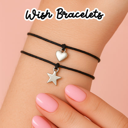 A close-up of a person's wrist wearing a black bracelet with a silver heart charm and a silver star charm.